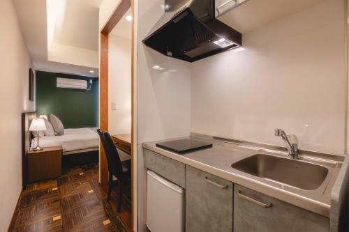 una piccola cucina con lavandino e una camera con letto di Centurion Hotel Residential Akasaka Station a Tokyo