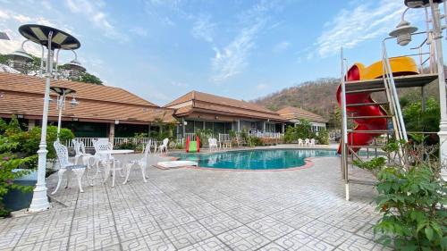a pool with a red slide and white chairs at Baan Dara Resort in Sara Buri