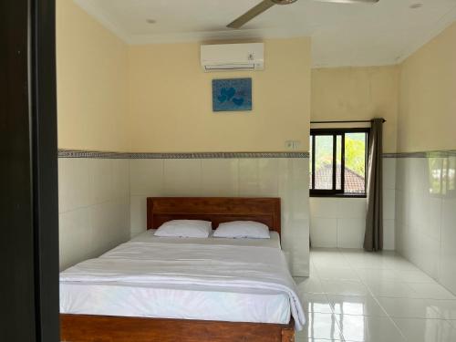 アメッドにあるOle Homestayの白いシーツと窓のあるベッドのある寝室