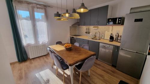 Il comprend une cuisine avec une table et des chaises en bois ainsi qu'une cuisine équipée d'un réfrigérateur. dans l'établissement T3 au calme à deux pas de la mer, à Nice