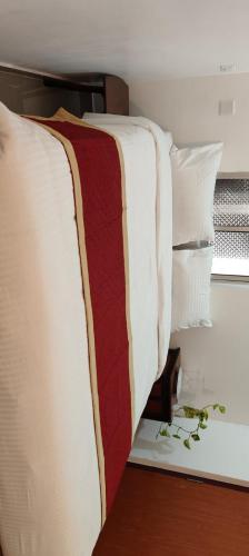 a bed with white and red sheets and pillows at Paradise White Town Villa 1BHK in Kottakupam