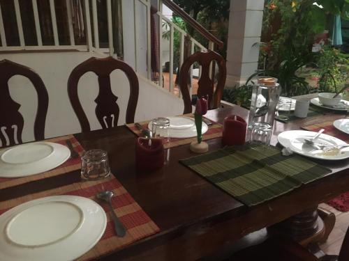 a wooden table with white plates on top of it at Bloom Garden Bed & Breakfast in Siem Reap