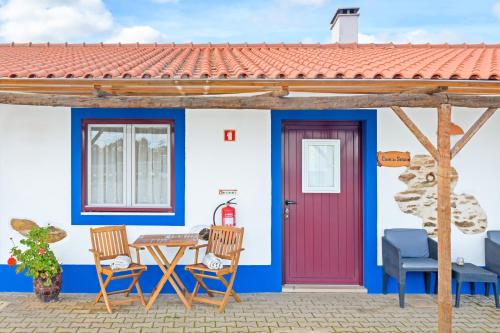 a house with a red door and a table and chairs at Herdade Vale de Gaios in Odemira