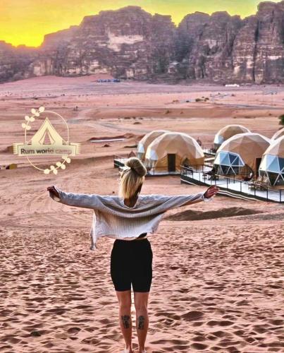 a woman standing on the beach with her arms outstretched at RUM WORLD BUBBLE lUXURY CAMP in Wadi Rum