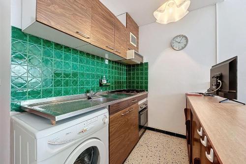une cuisine avec une machine à laver et une horloge au mur dans l'établissement Spacious house near the beach, à Port-la-Nouvelle