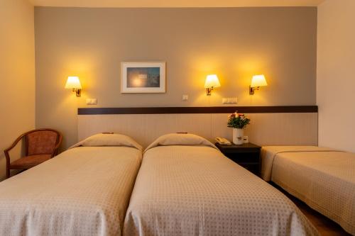 a hotel room with two beds and two lights at Queen Olga Hotel in Thessaloniki