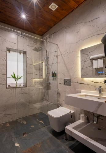 a bathroom with a toilet and a sink and a shower at Tarangi Resort and Spa in Rāmnagar