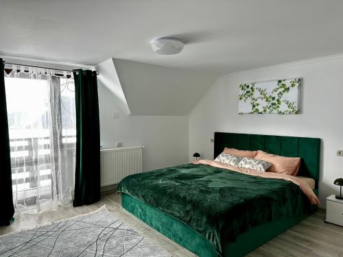 a bedroom with a green bed and a window at Casa Albă in Vatra Moldoviţei