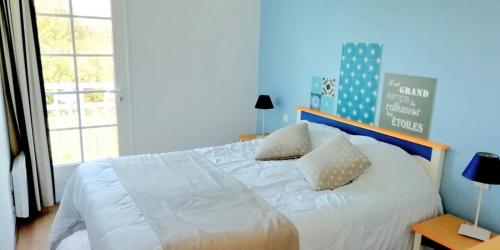 ein Schlafzimmer mit einem Bett mit weißen Laken und Kissen in der Unterkunft "ENTRE GREENS ET VAGUES" Maison de vacances, cœur d'un golf, résidence privée, accès piscines gratuit in Talmont