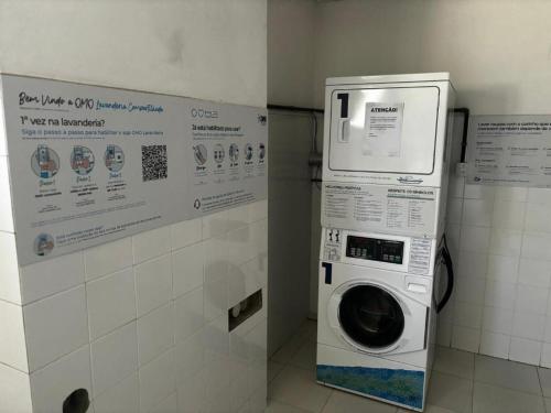 a washing machine in a bathroom with a sign at Via Park Flat PARAÍSO in Campos dos Goytacazes