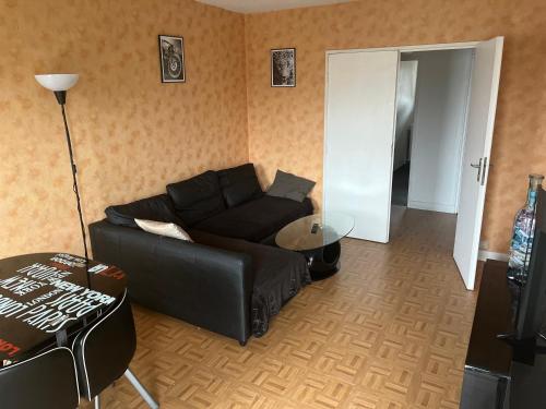 un salon avec un canapé noir et une table dans l'établissement Spacieux appartement 3 chambres, à Massy