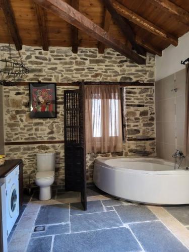 baño de piedra con bañera y aseo en Rustic House, en Eleftheroúpolis