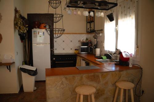 a kitchen with a counter and a refrigerator and stools at Casa rural de encanto en plena Serranía de Ronda in Ronda