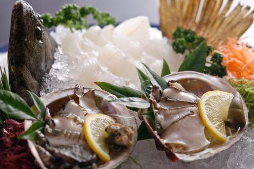 a oyster with lemon slices on a plate with other foods at Tabinoyado Ushionoakari Geiboso in Shima