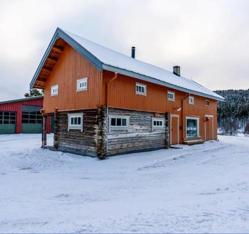 a large wooden barn with snow on the ground at Leilighet i stall fra 1800-tallet in Os
