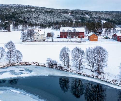 a snow covered field with a red barn and a lake at Leilighet i stall fra 1800-tallet in Os
