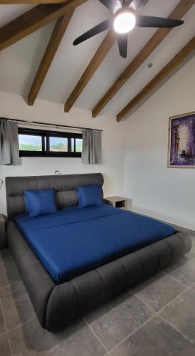 a bedroom with a large bed with a blue blanket at RésidenceSuisse Roof-Top in Nosy Be