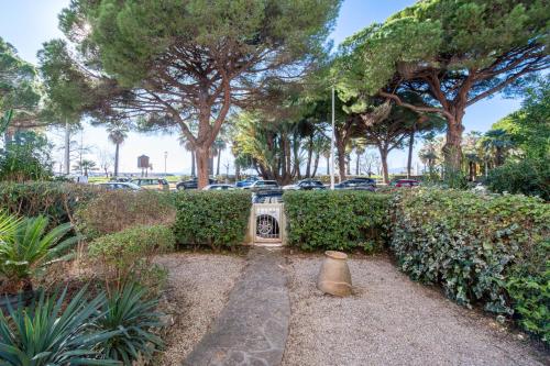 un jardin avec une statue et des arbres ainsi qu'un parking dans l'établissement Garden-Level Apartment in Palm Beach with Garage, à Cannes