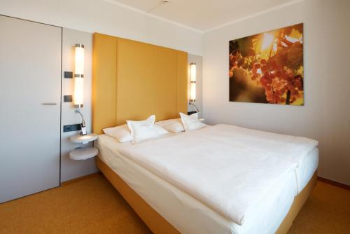 a bedroom with a large white bed with two pillows at Bio-Seehotel Zeulenroda in Zeulenroda