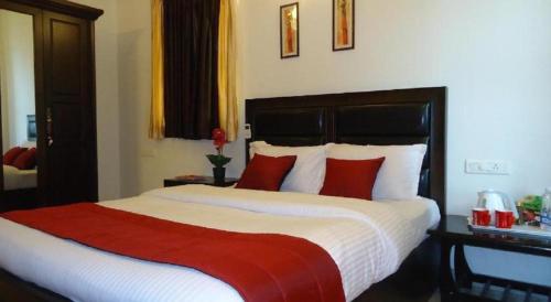 a bedroom with a large bed with red pillows at Oragadam Rooms By Actisai in Oragadam