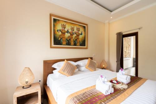 a bedroom with two beds and a picture on the wall at Oka Suite Sebatu Ubud in Tampaksiring