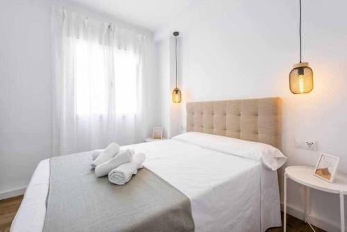 biała sypialnia z dużym łóżkiem i 2 białymi ręcznikami w obiekcie Precioso apartamento en el centro de Nerja w mieście Nerja