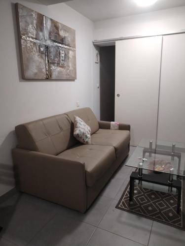 a living room with a brown couch and a table at Magistic Handi in Perpignan