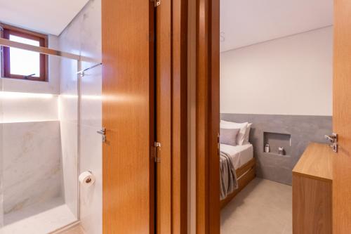 a bathroom with a glass door leading to a bedroom at O Melhor Lugar p/ Se Hospedar na Chapada Diamantina - Diamantino Residence - Lar Aconchego in Mucugê