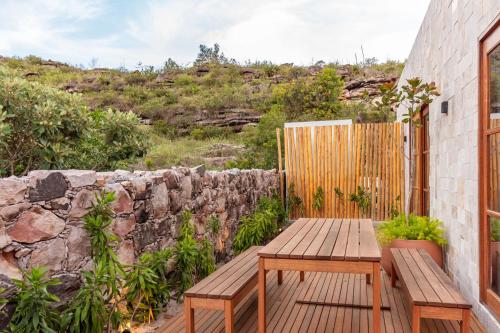 a patio with a wooden bench and a stone wall at O Melhor Lugar p/ Se Hospedar na Chapada Diamantina - Diamantino Residence - Lar Aconchego in Mucugê