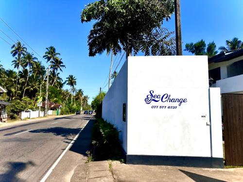 a white sign on the side of a road at Sea Change in Talpe