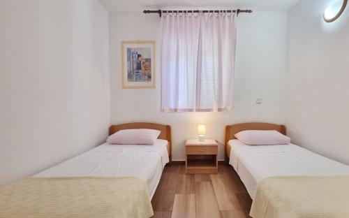 Dos camas individuales en una habitación con ventana. en Apartments Barbalic D, en Baška
