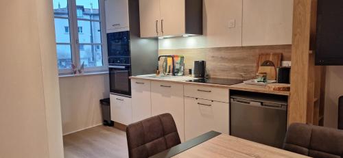 une cuisine avec des armoires blanches et une table avec des chaises dans l'établissement Le bouquet 6 personnes max, à Éveux