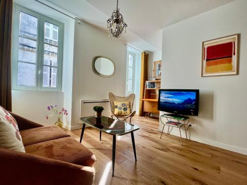 un salon avec un canapé et une télévision dans l'établissement Escapade Vintage avec terrasse en centre historique, à La Rochelle