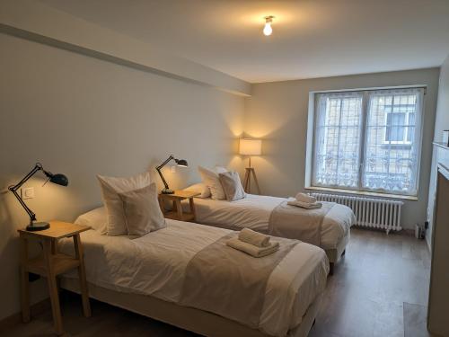 une chambre avec deux lits et une fenêtre dans l'établissement Maison de ville située à 8 kms du Mont St Michel, à Pontorson
