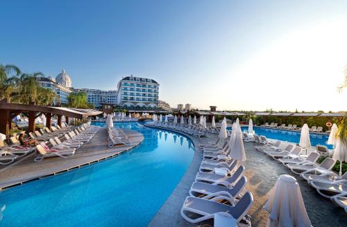 a swimming pool with lounge chairs and umbrellas at Adalya Elite Lara Hotel - Ultra All Inclusive in Lara