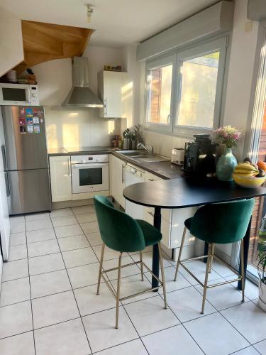 une cuisine avec une table et deux chaises vertes dans l'établissement Pablo house - 24h du mans, au Mans