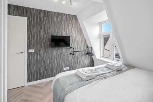 a bedroom with a bed and a tv on a wall at Unique Penthouse Near City Center And Park in Roosendaal