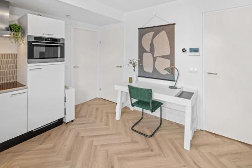 a white kitchen with a desk and a green chair at Unique Penthouse Near City Center And Park in Roosendaal