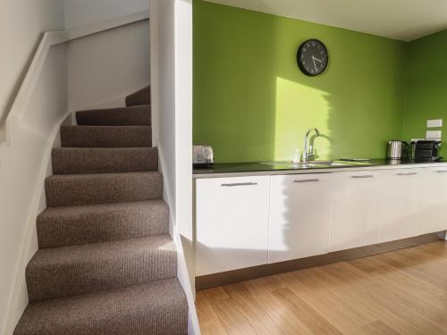 a staircase in a kitchen with a sink and a clock at Loch View in Breaclete
