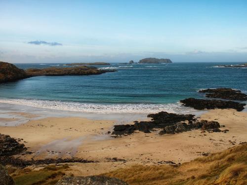 a beach with rocks in the water and the ocean at Loch View in Breaclete