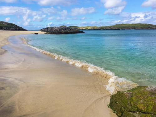 a sandy beach with the ocean and rocks at Loch View in Breaclete