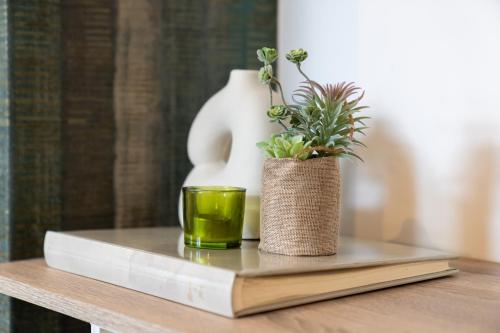a book and a cup on a table with a plant at Unique Penthouse Near City Center And Park in Roosendaal