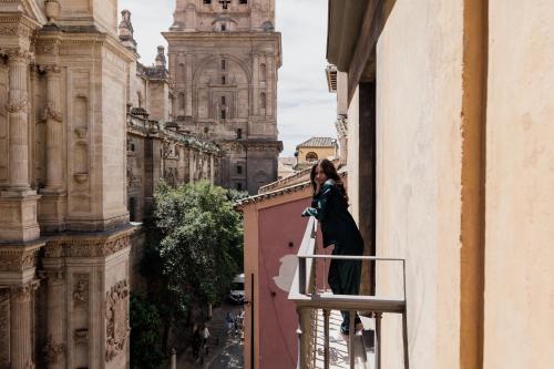 a woman standing on a balcony looking out of a window at Áurea Catedral by Eurostars Hotel Company in Granada