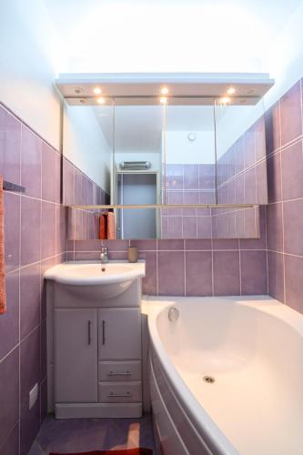 une salle de bain avec une baignoire, un lavabo et un miroir dans l'établissement MARINA, au Cap d'Agde