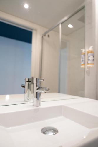 a bathroom sink with a faucet and a mirror at The Central House Lisbon Baixa in Lisbon