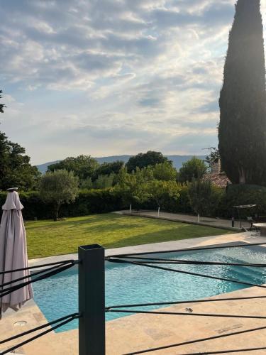 a swimming pool with an umbrella next to a garden at Villa Élégante à Berre-les-Alpes - Terrasse, Piscine & Vue Panoramique in Berre-les Alpes