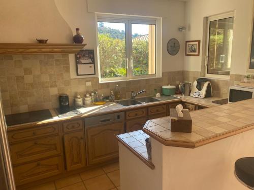 une cuisine avec des armoires en bois, un évier et une fenêtre dans l'établissement Villa avec piscine vue mer 4 chambres à Saint-Clair Le Lavandou, à La Celle-sous-Gouzon