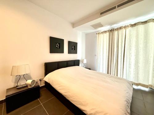 une chambre avec un grand lit et une fenêtre dans l'établissement Sliema 1BDR Apartment with Pool Access and off Seafront, à Sliema
