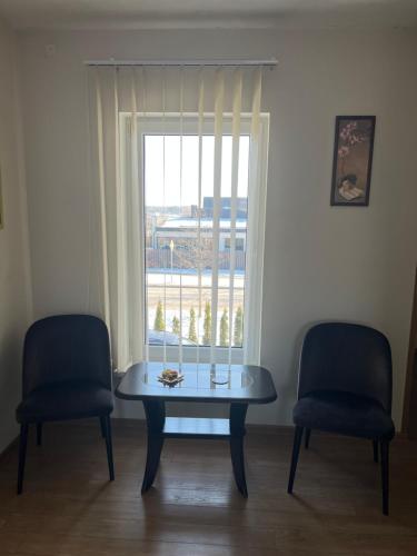 a table and two chairs in a room with a window at Pilaites svetingi namai in Vilnius