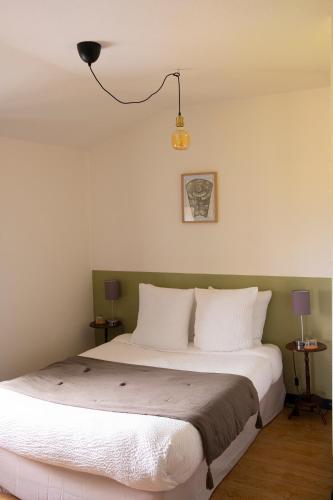 une chambre avec un grand lit avec des oreillers blancs dans l'établissement L'Auberge du Campos, à Saint-Pierre-Duchamp